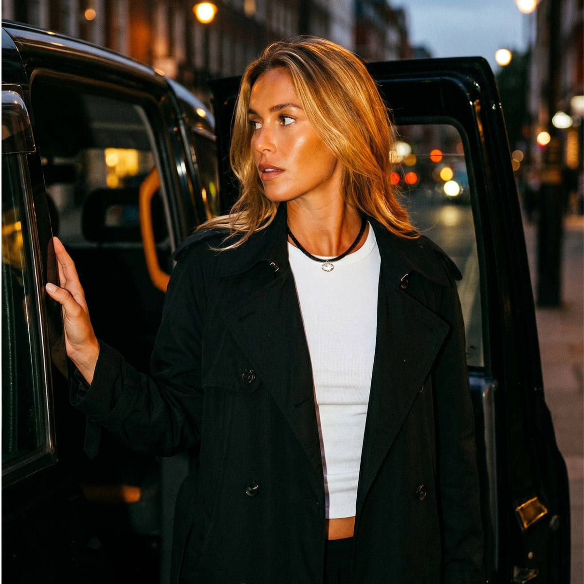 Woman getting out of a black car in an urban setting